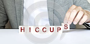 Word HICCUPS made with wood building blocks