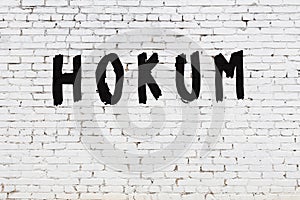 Word hokum painted on white brick wall