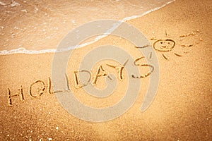 The word holidays written in the sand on a beach