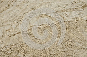 Word holidays written on sandy beach