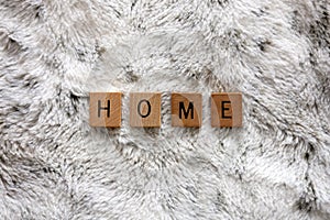 Word Home Spelled out in Wooden Letter Tiles on Cozy Faux Fur Blanket Background