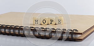 Word HOPE made with letters on wooden blocks on wooden notepad