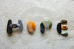 Word: HOPE, written using colored stones on white sand