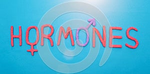 The word hormones from red plasticine on a blue background concept of all human hormones, inscription