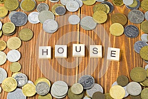 Word HOUSE on wooden cube with coins frame at wood background. Savings plans for housing financial concept