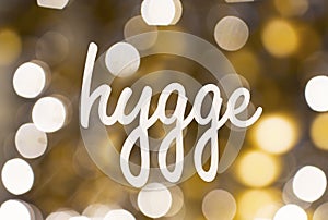 Word hygge over blurred golden lights background