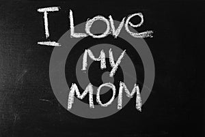 The word i love mom written in white chalk on a black board