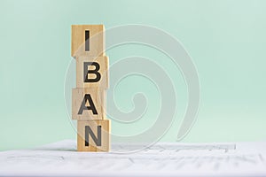 word IBAN with wood building blocks, light blue background. document with numbers on background, business concept. space