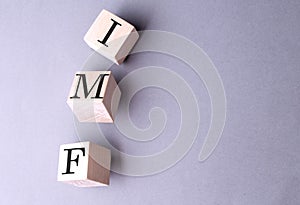 Word IMF on wooden block on the grey background