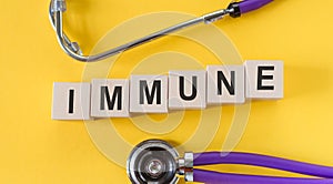 The word immune made from wooden cubes on a yellow table with a stethoscope. Medical concept