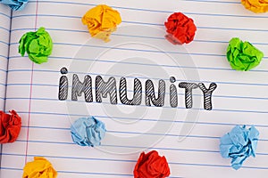 The word Immunity on notebook sheet with some colorful crumpled paper balls around it