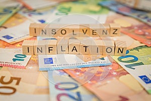 The word Inflation and Insolvenz - in German for Insolvency - in the background on banknotes Euro notes written with wooden dice t