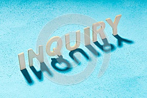 The word inquiry is composed of wooden letters on a blue background