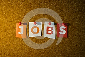 The word Jobs written on colorful note papers on board background. Employment concept. Job search