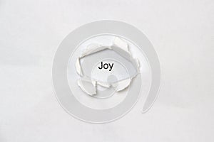 Word joy on white isolated background through the wound hole in the paper.