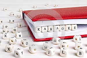 Word Karaoke written in wooden blocks in red notebook on white w