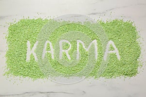 Word Karma made of sea salt on white marble table, top view