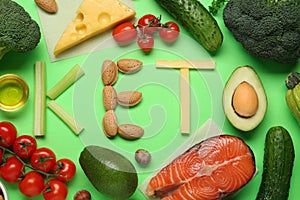 Word Keto made with products surrounded by different food on light green background, flat lay