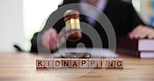 Word Kidnapping made of wooden cubes on table in law court