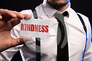 word kindness written on a white sheet of paper held by a man. High quality photo