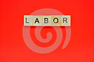 Word labor. Top view of wooden blocks with letters on red surface