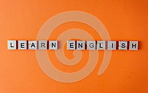 Word learn English. Motivation. The phrase is laid out in wooden letters top view. Motivation. Orange flat lay