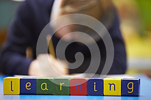 Word Learning Spelt In Wooden Blocks With Pupil Behind