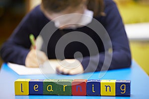 Word Learning Spelt In Wooden Blocks With Pupil Behind