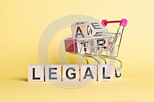 The word LEGAL on wooden cubes, on a yellow background with a shopping trolley