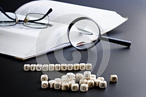 Word linguistics made up of cubes next to open book, pen, magnifying glass and glasses. Concept of studying the humanities and