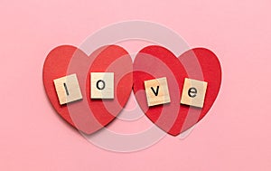 The word Love, laid out in wooden cubes on two red hearts. A declaration of love to your girlfriend, boyfriend, for a romantic