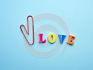 Word love made of multi-colored wooden letters and a red paper clip in the shape of a heart