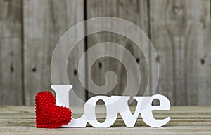 The word Love with red heart and wooden background