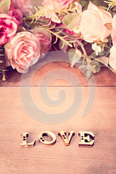 Word Love with rose flower on wood table,