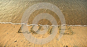 Word love in the sand at the beach on Valentine Day.