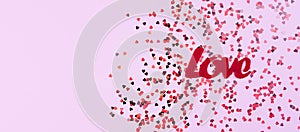 A word LOVE and small red hearts on the pink background. Composition for Valentine\'s Day. Flatlay. Banner. Top view.