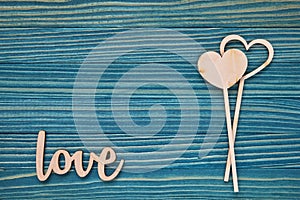 The word Love and two hearts on a blue wooden background