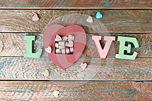 The word love from volume letters, sweet vitamins in the shape of a heart, top view