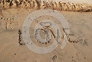 Word LOVE on wet sand