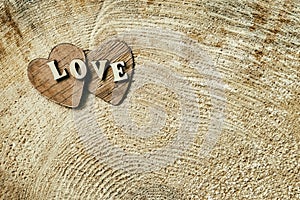 Word love from wooden letters on two wooden hearts, on wooden surface of saw cut, grunge texture , background