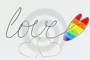 The word Love is written in black marker with a heart painted in the colors of the Lgbt flag rainbow heart shape on white. Concept