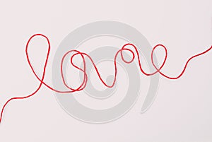 Word love written with red wool thread on white