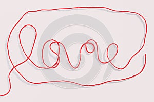 Word love written with red wool thread on white