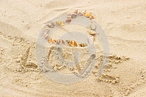 Word love written on sand at the beach, heart of shells