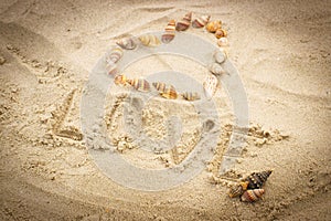 Word love written on sand at the beach, heart of shells