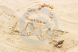 Word love written on sand at the beach, heart of shells