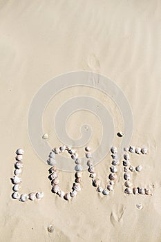 Word love written on the sand with sea shells at sunset on the beach