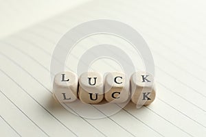 Word LUCK made with wooden cubes on open notebook, closeup