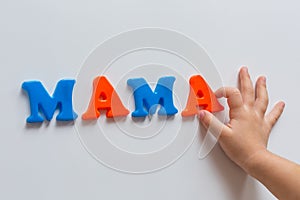 The word MAMA is made of colored magnetic letters typed by a child`s hand. Mother`s day.