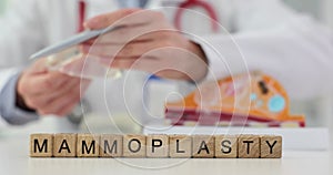 Word mammoplasty written on cubes near doctor with breast implant 4k movie slow motion